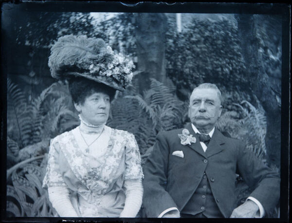 Glass plate negative of wealthy Victorian couple with the Lady wearing a large, flowery hat